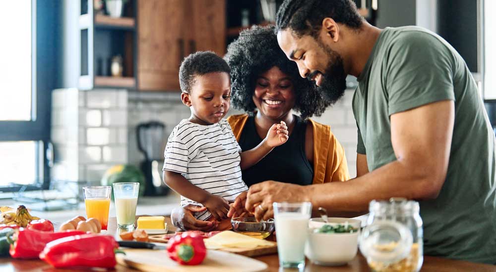 Man with woman and toddler in kitchen with healthy food and drinks