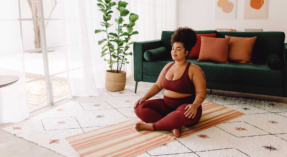 woman with closed eyes sitting cross legged on yoga mat
