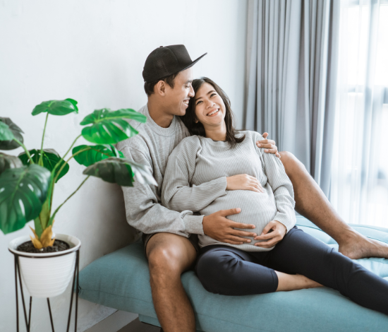 man and pregnant woman sitting on the couch